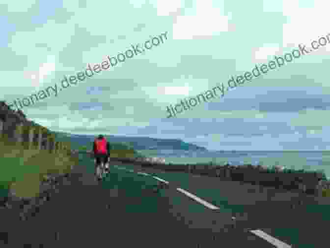 A Cyclist Riding Along The Scenic Coastal Road In Ireland, With The Atlantic Ocean And Mountains In The Background. The Wild Atlantic Way And Western Ireland: 6 Cycle Tours Along Ireland S West Coast (Cicerone Cycling Guides)
